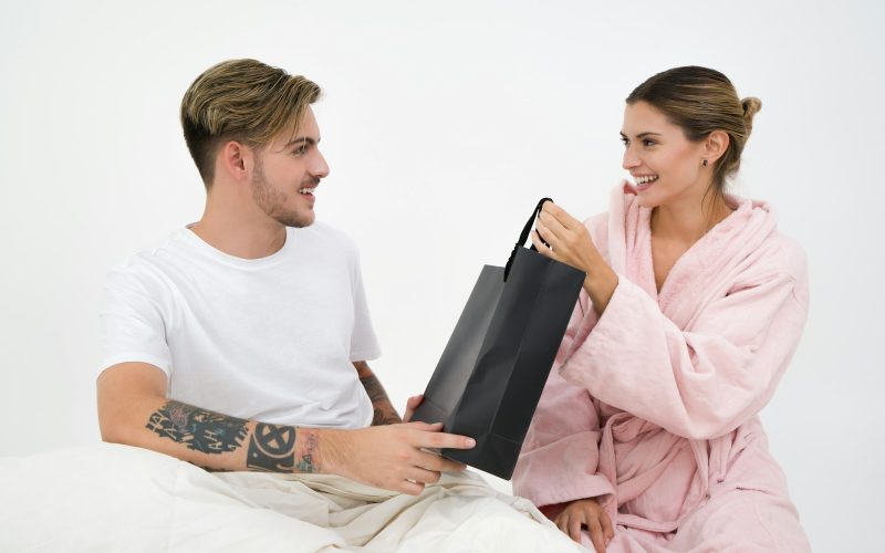 woman holding black paper bag sitting in front of the man