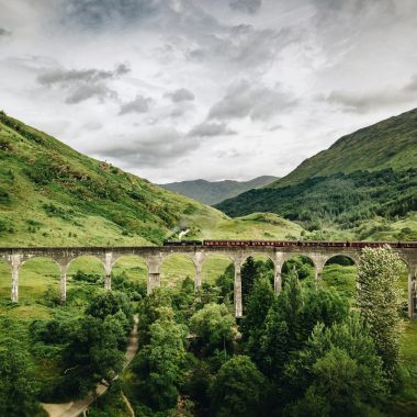 train passing by bridge over mountains