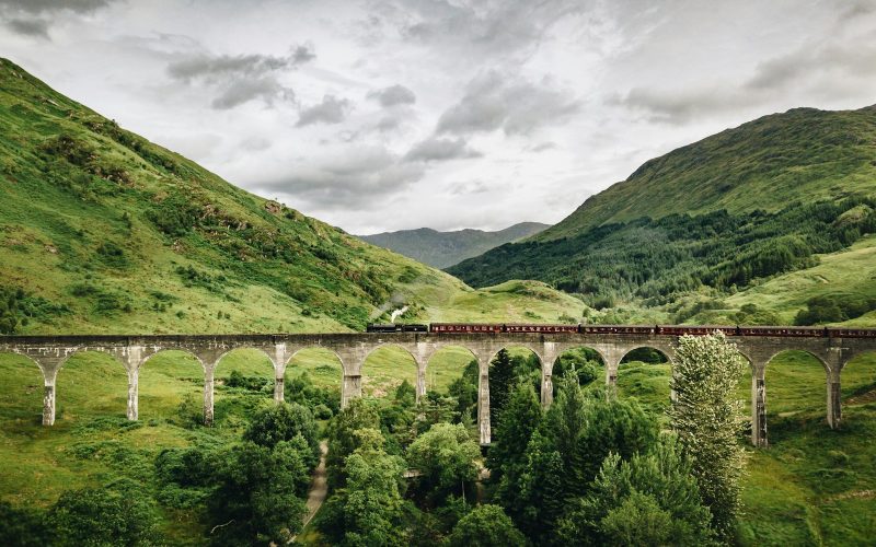 train passing by bridge over mountains