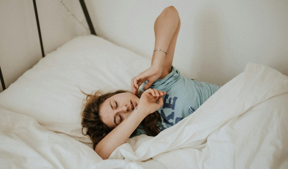 woman covered in white blanket sleeping on white bed comforter