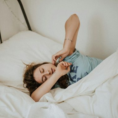 woman covered in white blanket sleeping on white bed comforter