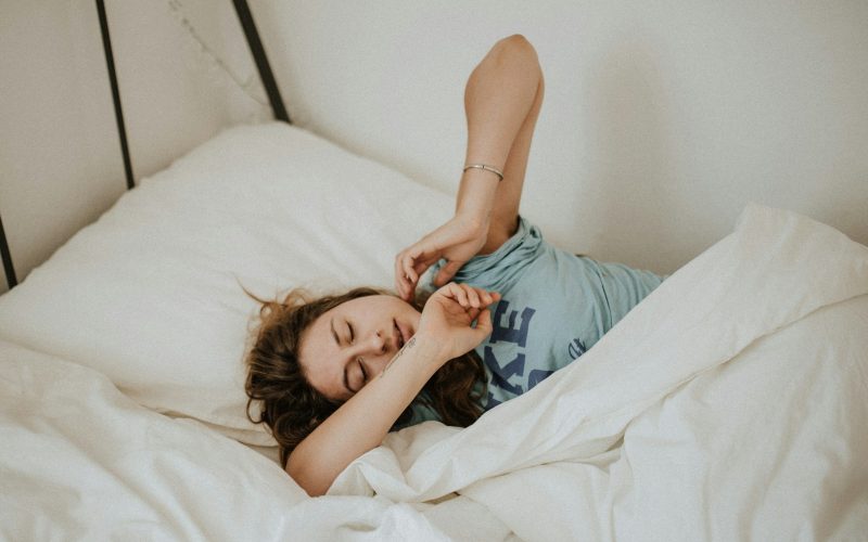 woman covered in white blanket sleeping on white bed comforter