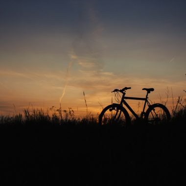 a bike is sitting in the grass at sunset