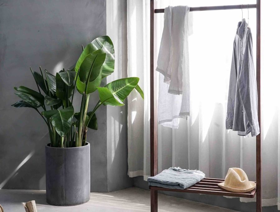 gray dress shirt hang on brown wooden rack in front of window with white curtain