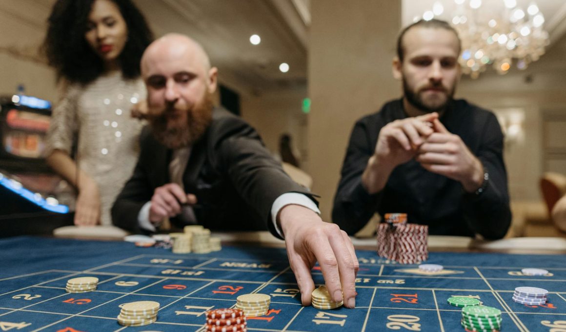 Three adults playing roulette at a casino, focused on placing bets with gaming chips.