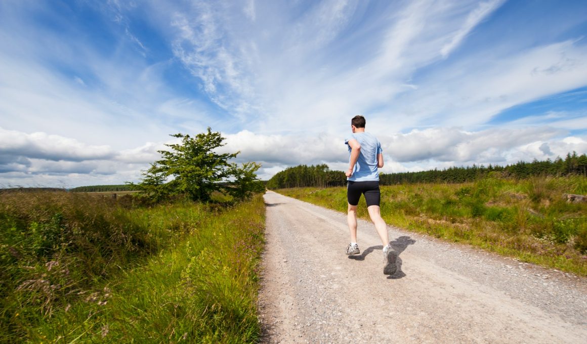man running on road near grass field