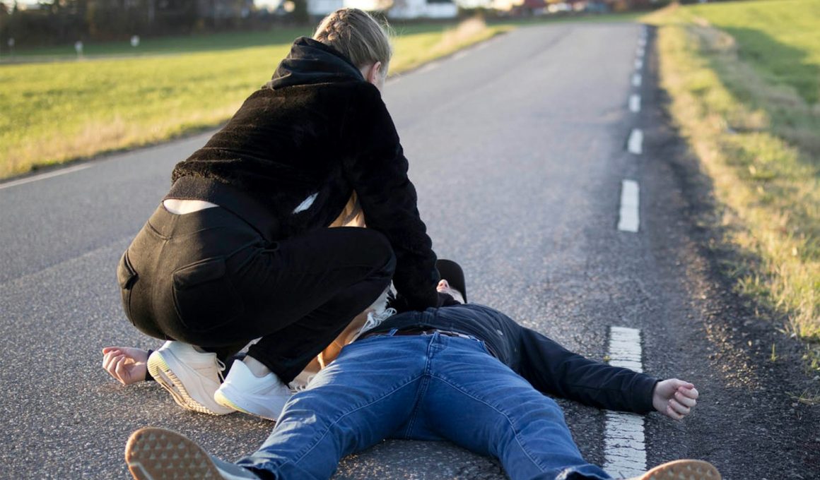a man kneeling on the side of a road with another man kneeling on the ground