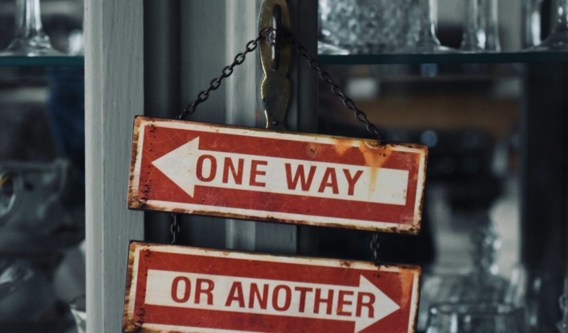 two red and white signs hanging from a metal pole