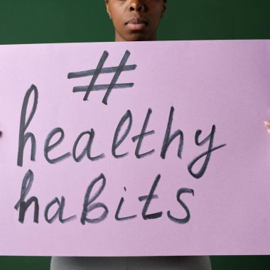 Person holding a "#healthyhabits" sign, emphasizing wellness.