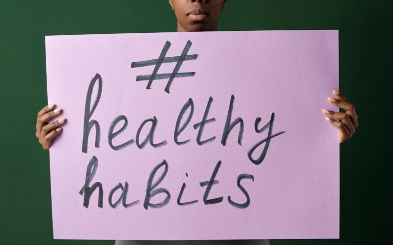 Person holding a "#healthyhabits" sign, emphasizing wellness.