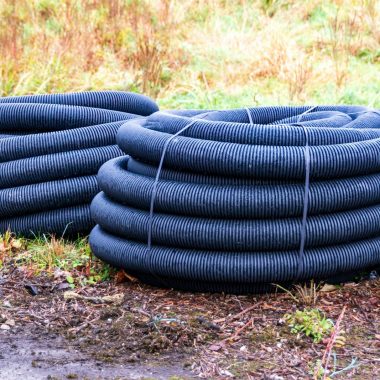 Two coiled black drainage pipes on the ground.