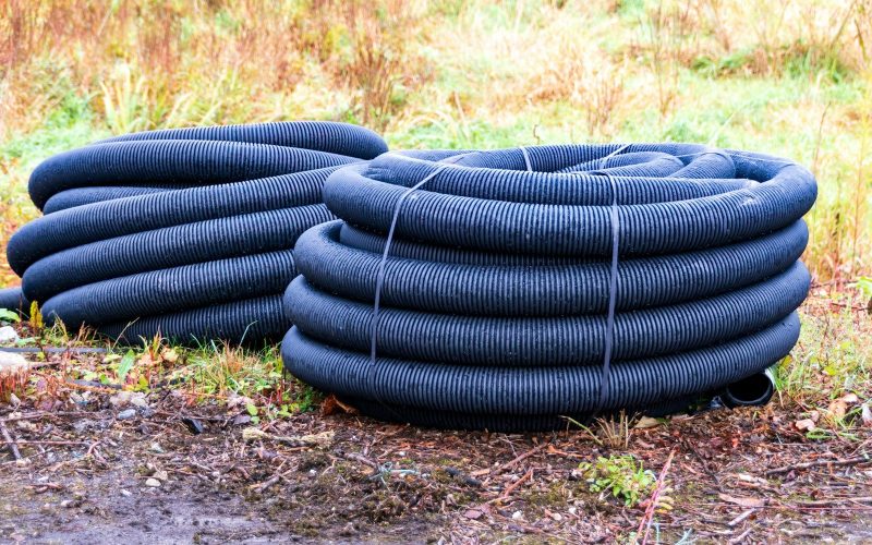 Two coiled black drainage pipes on the ground.