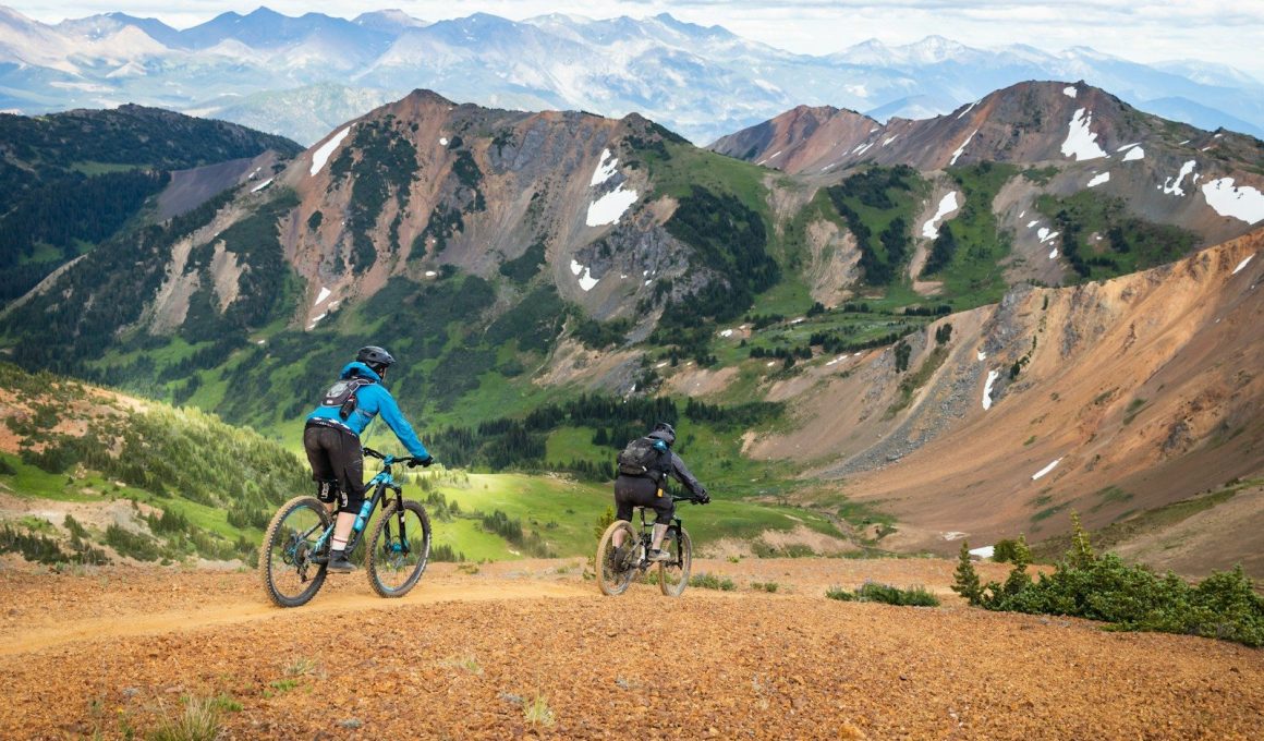 man in blue jacket riding bicycle on dirt road during daytime