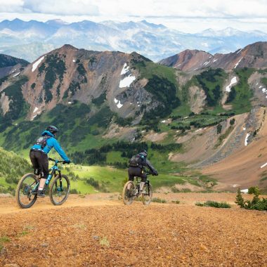 man in blue jacket riding bicycle on dirt road during daytime