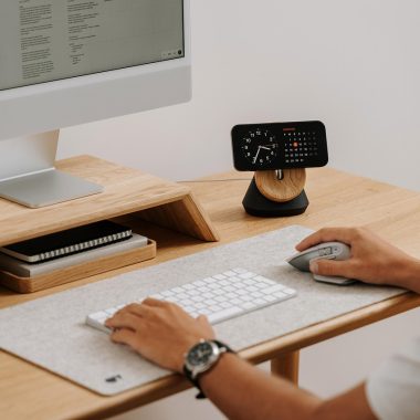 Man aan een opgeruimde thuiswerkplek met laptop op standaard en bureaulamp