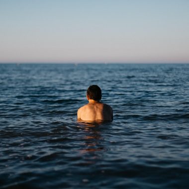 Man in zwembroek op het strand bij zee