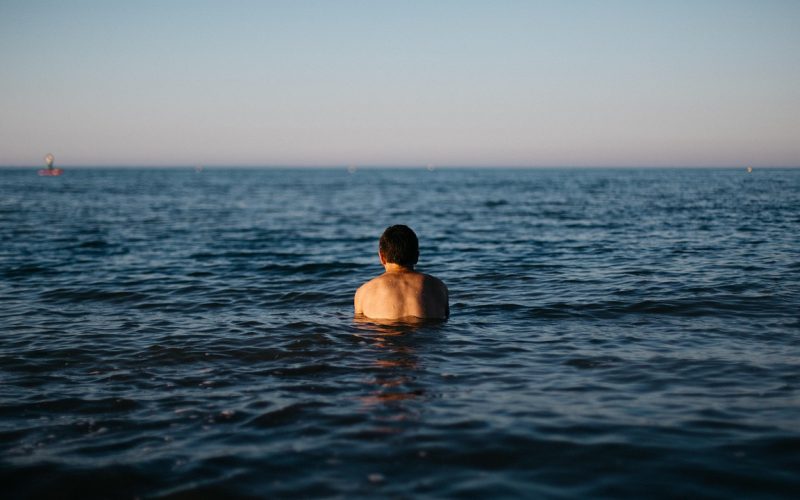 Man in zwembroek op het strand bij zee