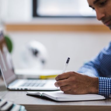 Man die zijn laptop opruimt en bestanden organiseert aan een bureau