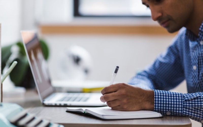 Man die zijn laptop opruimt en bestanden organiseert aan een bureau