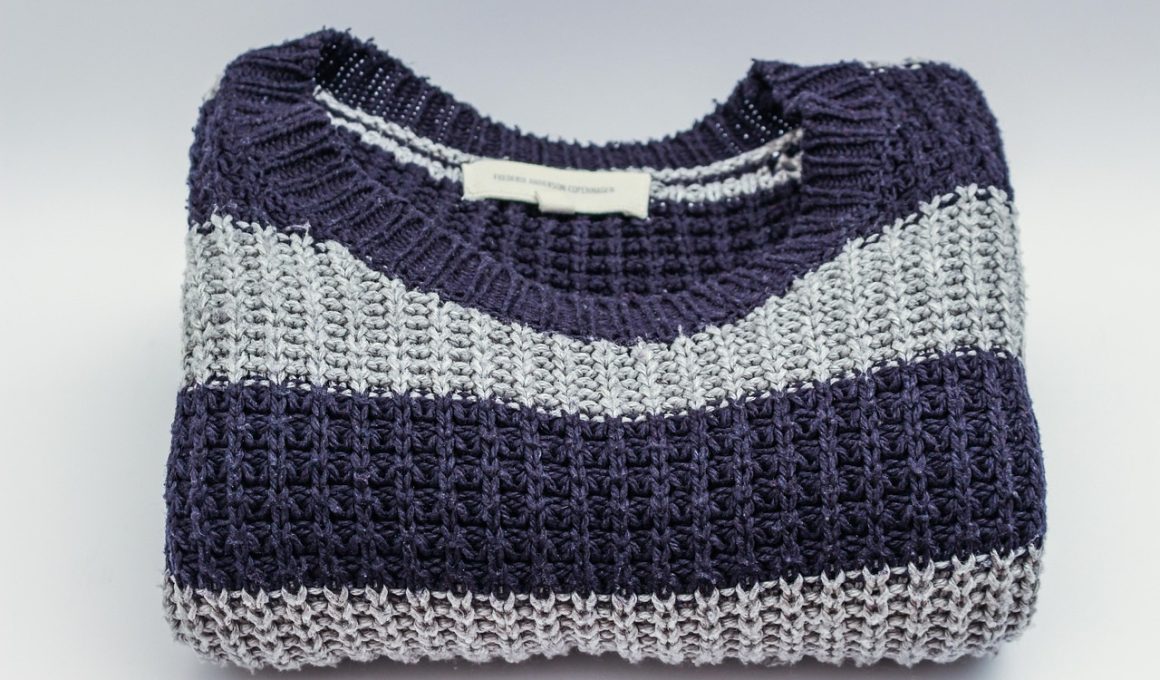 Neatjes gevouwen merino wollen trui in neutrale kleur op een houten ondergrond
