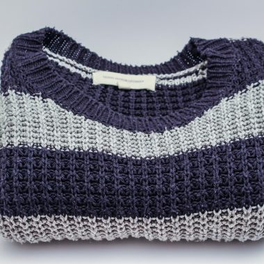 Neatjes gevouwen merino wollen trui in neutrale kleur op een houten ondergrond