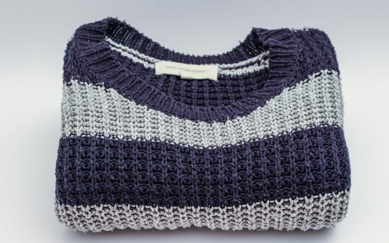 Neatjes gevouwen merino wollen trui in neutrale kleur op een houten ondergrond
