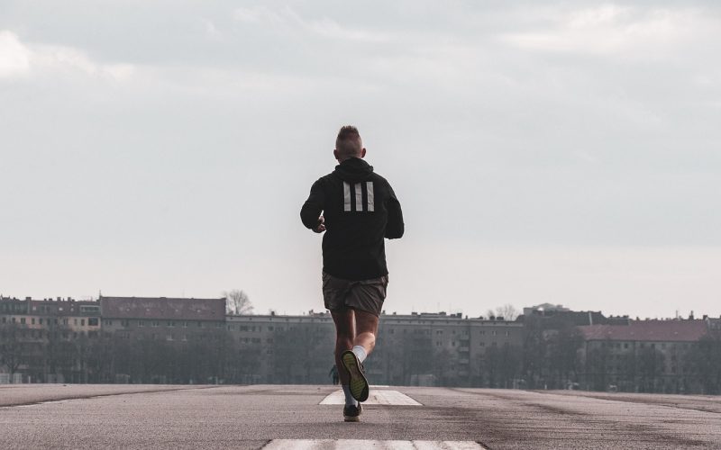 Hardloper op een donkere herfstavond met reflecterende kleding op een natte weg